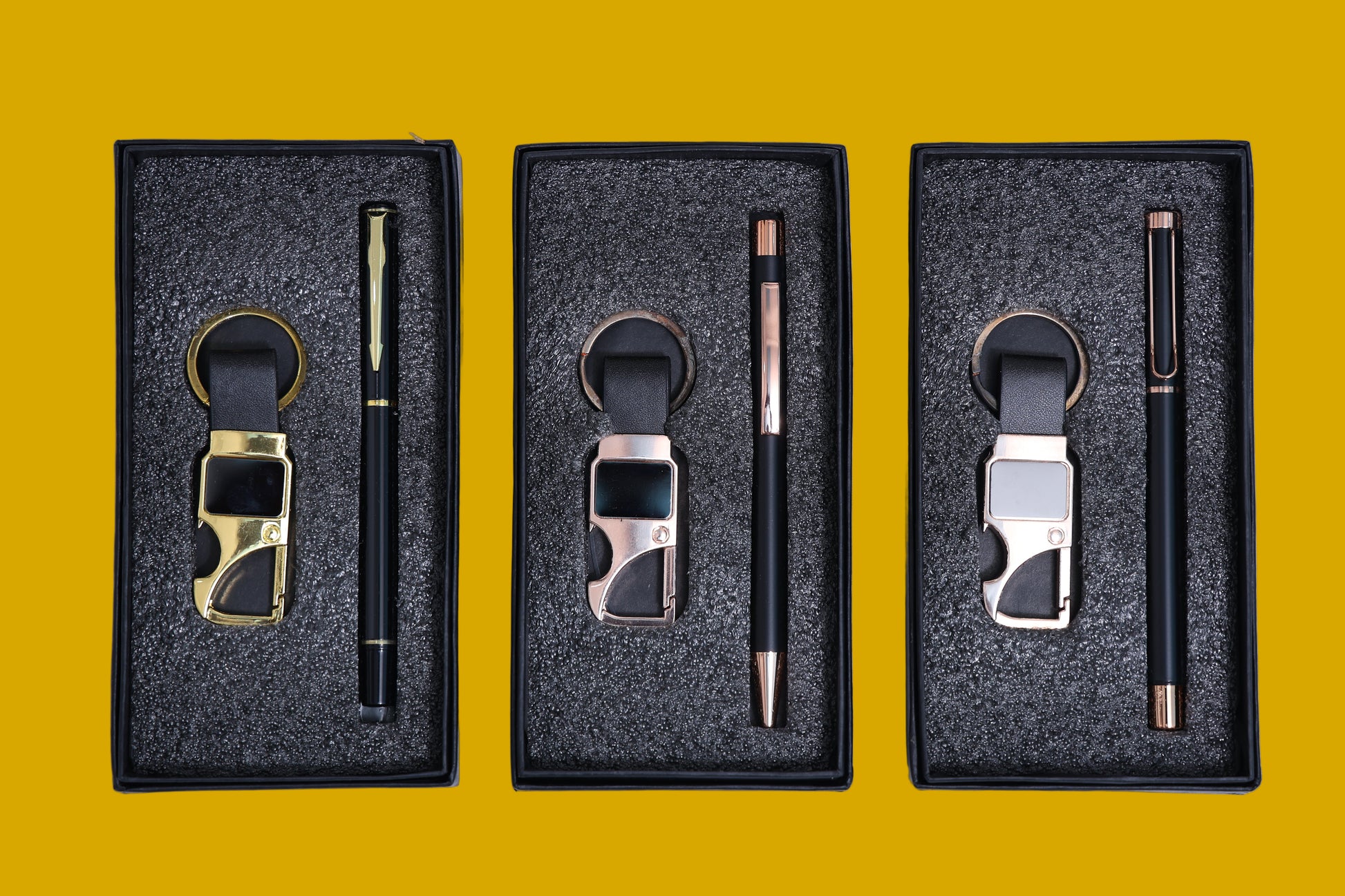 Three sets of keychains and pens in black boxes.