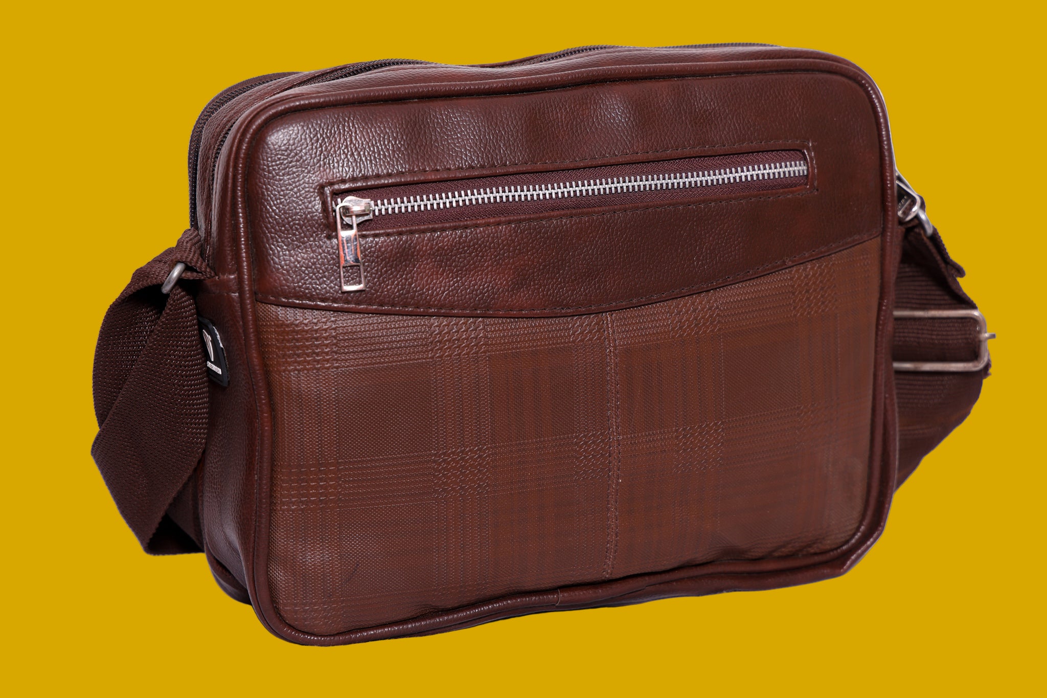 Brown leatherette bag with a visible zipper on a mustard background