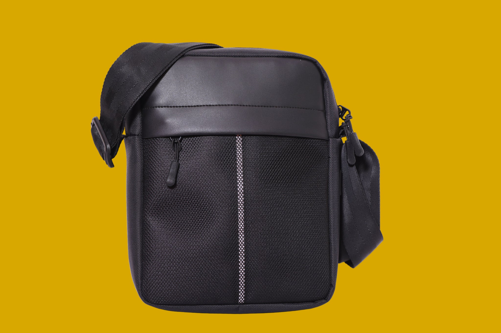 Black leatherette, vegan crossbody bag on a mustard background